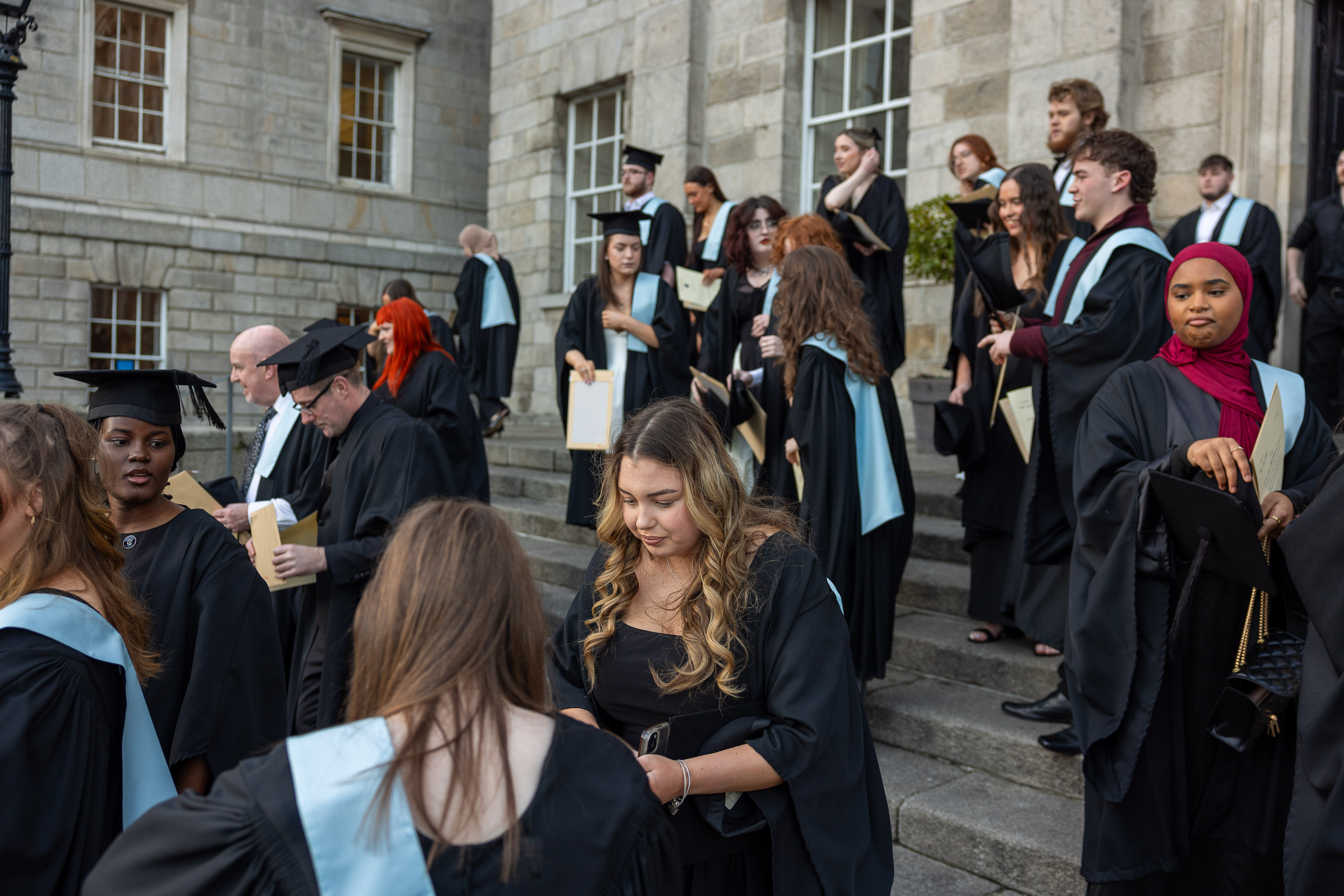 students in graduation gowns on the steps of a building